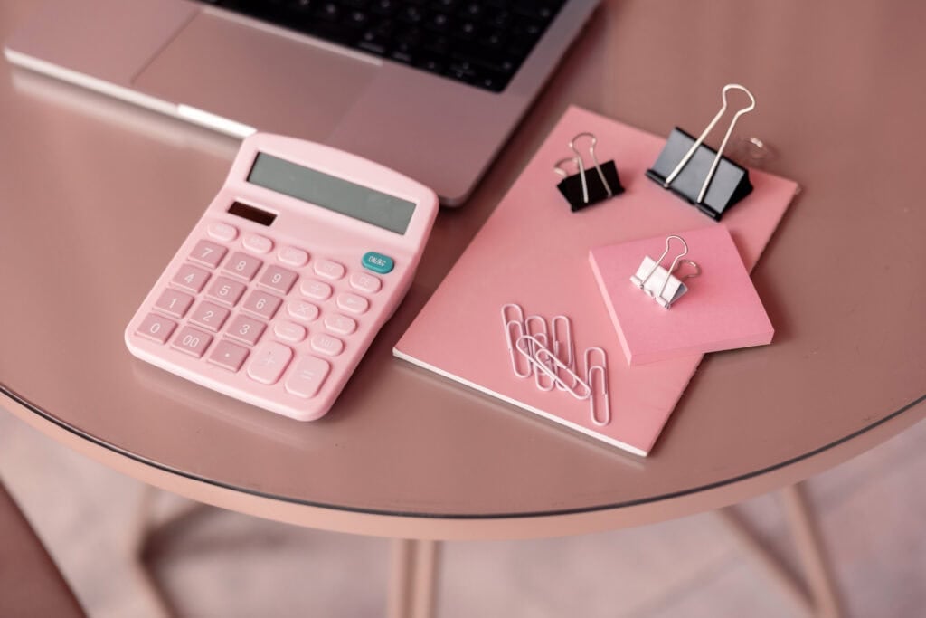 pink calculator and note pad on desk